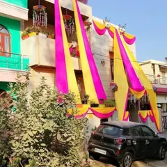 A full view of a house decorated for a wedding celebration. The vibrant pink and yellow drapes make the house stand out and create a welcoming atmosphere for guests.