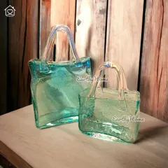 The glass handbag vase shown against a rustic wooden background. Its iridescent finish and unique shape make it a stunning decorative item.