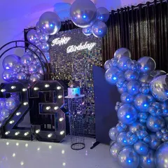 A full view of the modern 23rd birthday party setup, with large marquee numbers, a silver sequin wall, and dramatic silver chrome balloon garlands.
