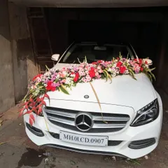 A luxurious floral arrangement for a white Mercedes-Benz. We used a vibrant mix of red, pink, and white flowers to create a full and colorful display across the front of the car.