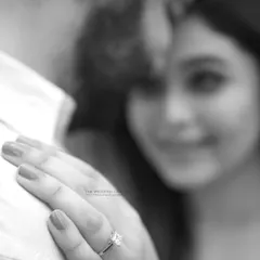 The engagement ring is a symbol of a promise. This detailed shot focuses on the ring while keeping the couple's soft-focus embrace in the background, telling a story of commitment.