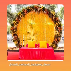 A classic Haldi backdrop with a large ring made of marigolds and a screen of genda phool strings. The simple yet elegant low seating with bright yellow cushions completes this traditional look.