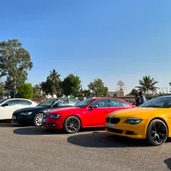 A colorful lineup of German performance sedans, including models from Audi and BMW, parked at the venue during a club meetup.