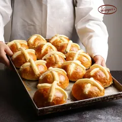 A tray of our Hot Cross Buns, fresh out of the oven. You can see the soft, glazed tops and the distinct pastry cross that makes this Easter treat so special.