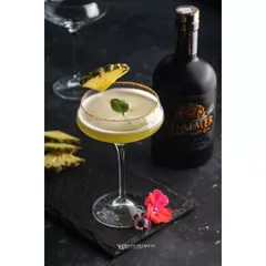 A pineapple gin cocktail, expertly garnished and ready to be served. This image, shot for Whiskey Amour, uses a dark setting to make the drink's color and form stand out.
