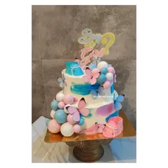 Boy or Girl? This two tier gender reveal cake is a whirlwind of fun, decorated with pink and blue splashes of color, delicate butterflies, and tiny fondant baby booties.