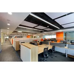 A wide view of the open-plan office floor, featuring rows of modular workstations with low partitions to encourage communication. The design includes pops of brand color and varied ceiling textures for acoustic control and visual interest.