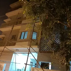 A night-time photo of a residential project under construction in Bangalore. This image captures the building's form taking shape, including the intricate jali screen feature.