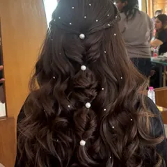 This is a dreamy half-up style with a fishtail braid down the center, accented with large and small pearls. The soft waves and scattered pearls create a magical, ethereal look perfect for a Sangeet or engagement party.