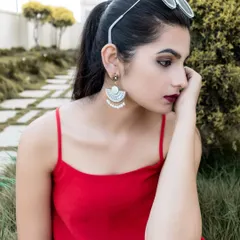An outdoor portrait titled 'FADED BLOSSOM'. The model's pensive look, combined with the natural garden setting and stylish accessories, creates a moody and fashionable image.