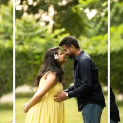 A sweet, intimate moment between a couple during their outdoor maternity shoot. The natural green background and soft light create a romantic and relaxed feel.