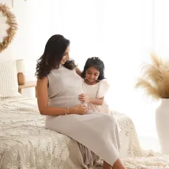 A sweet moment between mother and daughter. The little one's curiosity and gentle touch on the baby bump is a precious memory of her excitement to become a big sister.