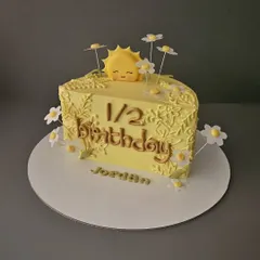 Rise and shine! A sunshine-themed half-birthday cake for Jordan. This chocolate praline cake is decorated with a cute sun and daisies.