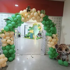 A welcoming arch for a jungle-themed first birthday. The organic arrangement of green and cream balloons, accented with tropical leaves, creates a perfect entrance to a wild and fun celebration.
