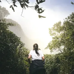 The final push to the summit. A trekker makes her way through the dense, misty forest path just before reaching the top of Skandagiri.