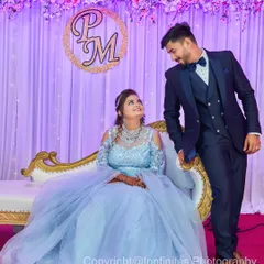 A classic reception portrait. The couple is elegantly dressed, posing on their stage with a custom monogram in the background.
