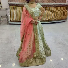 This elegant pista green lehenga with a contrasting peach dupatta is a popular rental for daytime events and sangeet functions. The light color and delicate gold motifs create a fresh and sophisticated look.