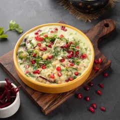 A vibrant bowl of Dahi Bhalla Chaat. I used a dark background to make the colors of the pomegranate seeds and green chutney pop, highlighting the dish's freshness and complexity.