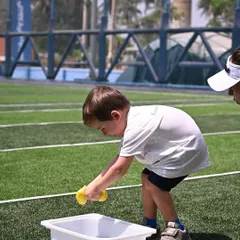 Another young athlete participates in the sponge-squeezing race. Our sports day activities are designed to be age-appropriate, ensuring everyone can participate and feel successful.