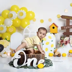 This one-year-old is ready to explore his lemonade stand setup, complete with a custom "One" sign and colorful props.