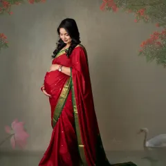 This portrait feels like a classic painting. The mom-to-be, dressed in a beautiful red and green saree, is captured in a moment of quiet reflection.