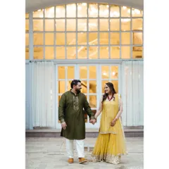 A sweet, candid moment during a mehndi celebration. The couple holds hands, sharing a look that speaks of shared joy and anticipation for the journey ahead.
