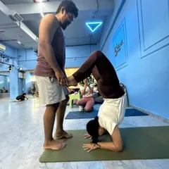 Safe, hands-on adjustments are a key part of learning. Here, I'm helping a student find stability and alignment in her headstand (Sirsasana), ensuring her foundation is strong and secure. This is a core skill we focus on in the teacher training course.