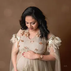 A close-up portrait in our beige gown with delicate feather and floral shoulder details, showcasing its unique and elegant design.