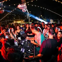 A wide shot of the rooftop Block Party at Raasta Bombay. The open-air setting, string lights, and packed crowd create a classic block party atmosphere right in the heart of the city.