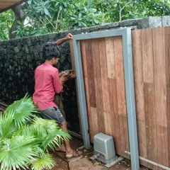 On-site in Alibaug, this image shows the installation of a wooden gate. It is a snapshot of the detailed craftsmanship and coordination required to execute design elements that blend natural materials with structural frames.