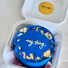A striking royal blue bento cake with the message "my king." The design is elevated with scattered gold leaf flakes and coordinating blue and gold sprinkles for a luxurious finish.