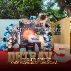 We turn imaginations into exquisite realities. This outdoor space-themed party for Dhirav's 5th birthday uses a large backdrop of the solar system, marquee letters, and balloon arches to create an impressive cosmic scene.
