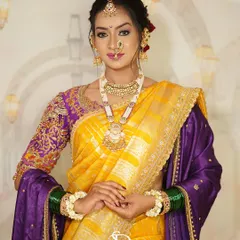 A full-length view of a traditional Marathi bride. The look is complete with a vibrant yellow and purple saree, green glass bangles, and floral bracelets, all tied together with flawless makeup.