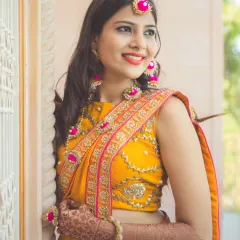 A beautiful portrait of a bride during her Haldi or Mehendi ceremony, dressed in a vibrant yellow saree with stunning floral jewelry.