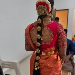 A full view of a traditional bridal hairstyle. This rental set includes the sun and moon hair pieces, the rakodi at the top, and the individual billai that go down the length of the braid.