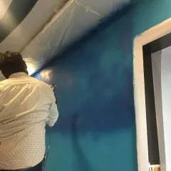 The beginning stages of a spray paint mural. Our artist uses an airbrush to create a smooth, blended background of a night sky, which will serve as the canvas for the main subject.