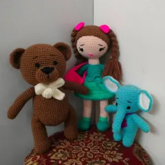 A cute doll with her two best friends, a little blue elephant and a brown teddy bear.