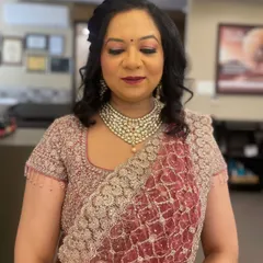 This is a classic party makeup look, perfect for a wedding guest or family member. The makeup features a soft shimmer on the eyes and a deep berry lip color that complements her embroidered saree.
