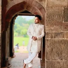 A groom's outfit should feel both powerful and comfortable. This ivory sherwani, seen here in a relaxed pose, is tailored for a perfect fit, allowing you to own your day with confidence and style.