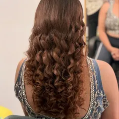 A detailed shot of the hairstyle for this look. These are perfectly defined, bouncy curls, styled into a high ponytail for a modern and chic party look.