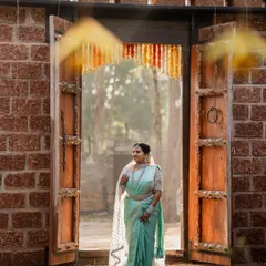 A sun-kissed bride framed by a rustic doorway. This portrait captures her serene beauty and the warm, natural light of an outdoor wedding venue.