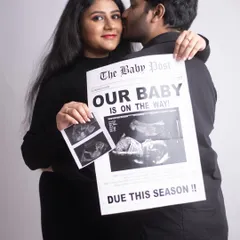 A sweet and intimate announcement photo. The couple holds their ultrasound pictures and a custom newspaper while sharing a happy kiss. It's a perfect blend of props and emotion.