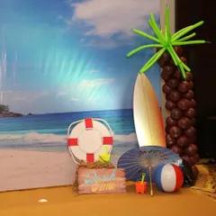For a Hawaiian-themed party, a photo booth is a must. I created this beach scene with a backdrop, surfboard, and fun props like a lifebuoy and beach toys.