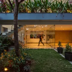 The entrance of this home is a transparent threshold between the garden and the interior. Glass walls and strategic lighting create an inviting glow, while tiered planters on the facade bring greenery to every level.