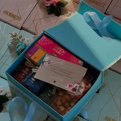 A chic and modern welcome box for wedding guests. The pastel blue box is personalized with the couple's names and filled with a curated selection of gourmet snacks and treats.