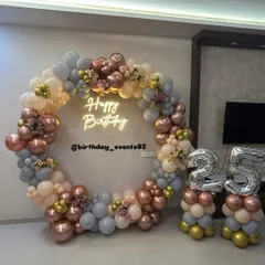 Our signature ring backdrops are a client favorite. This elegant setup features a full circle of pastel, rose gold, and grey balloons, a custom neon sign, and matching balloon stands for the birthday age, creating a polished and trendy photo corner.