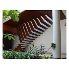 The underside of the recycled teak staircase in the "Boxed In House" reveals its structural artistry. Set against lush indoor plants, it demonstrates our focus on detailed craftsmanship and the integration of natural elements.
