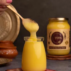 An action shot showing the rich, granular texture of the Vedic Wisdom ghee. This image focuses on the product's quality, making it look pure and wholesome.