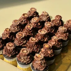 A tray of our decadent Ferrero Nutella cupcakes. They have a moist chocolate base, a ganache filling, and are topped with Nutella mousse and a Ferrero Rocher.