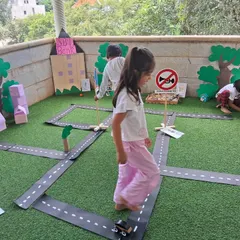 Imagination takes center stage in our miniature community role-play area. Children explore real-world concepts like road safety and community roles by driving toy cars through a town they helped create, turning abstract ideas into tangible fun.